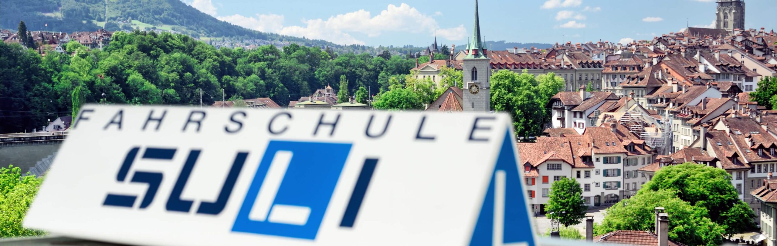 Blick auf die historische Stadt Bern, Standort einer Fahrschule in Bern, mit charakteristischen Häusern und Grünflächen im Hintergrund.