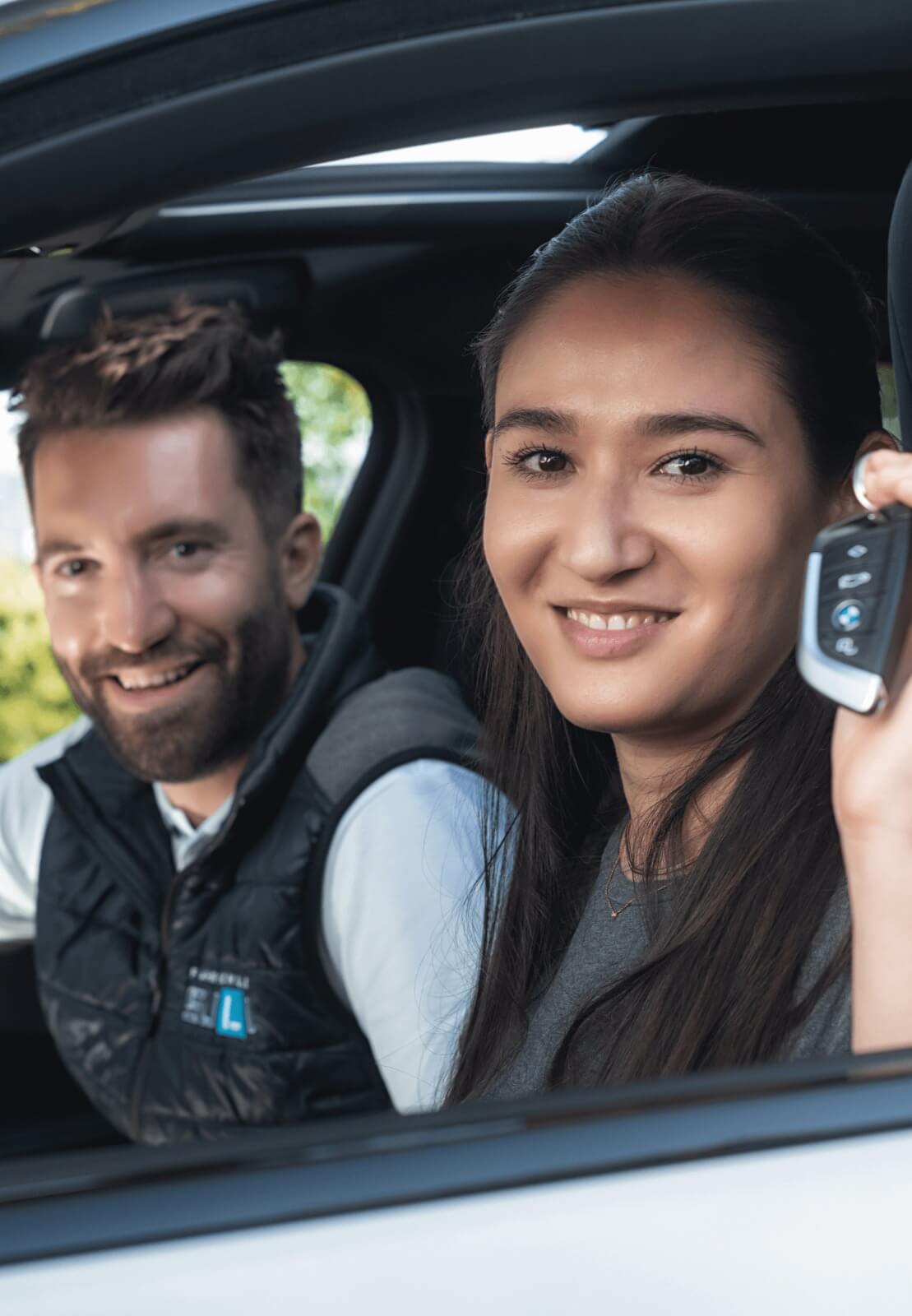 Fröhliche Fahrschülerin hebt den Schlüssel nach bestandener Fahrprüfung