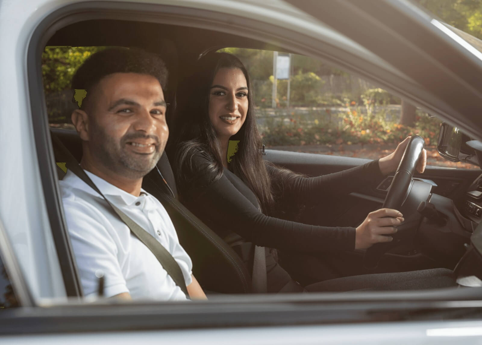 Fahrlehrer und Fahrschülerin lächeln – Ein angenehmes Lernumfeld.