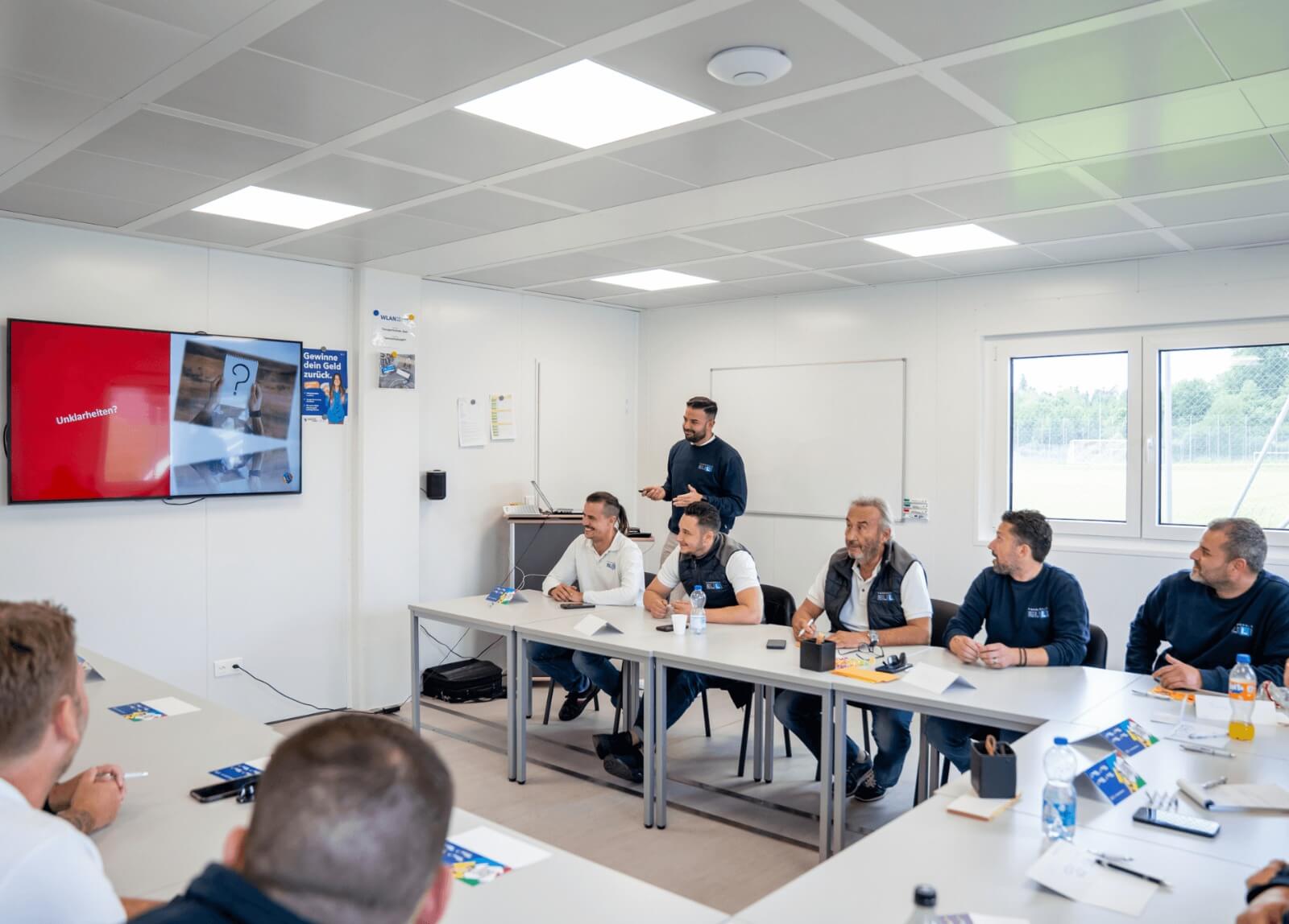 Fahrlehrerinnen sitzen zusammen bei einer internen Weiterbildung, lernen aktiv und tauschen sich aus.