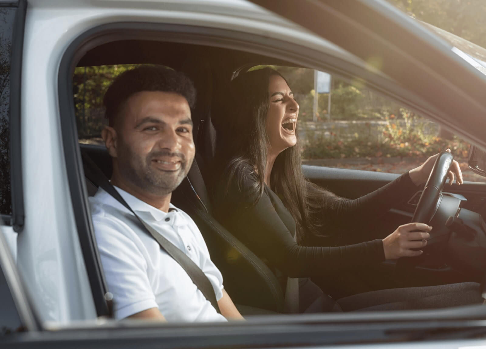 Dein Wohlbefinden steht bei uns an erster Stelle – Fahrlehrer mit lachender Fahrschülerin