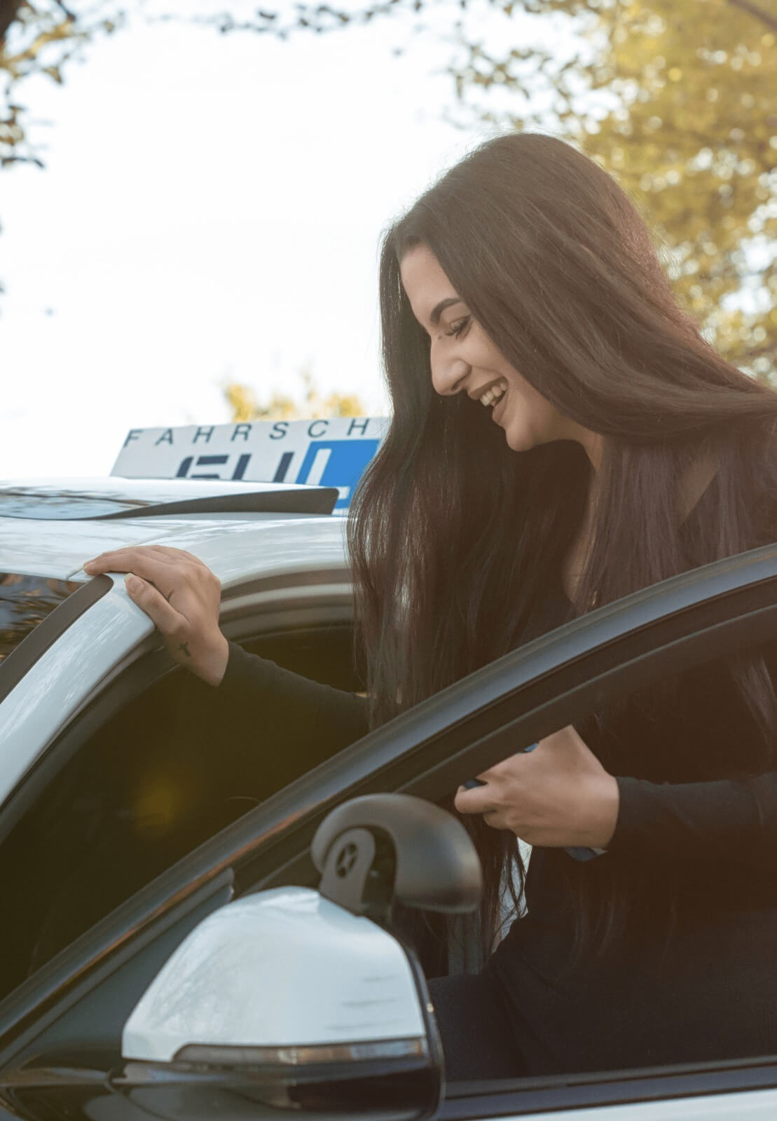Fahrschülerin steigt glücklich ins Auto ein – Unser Ziel: Dein Führerschein