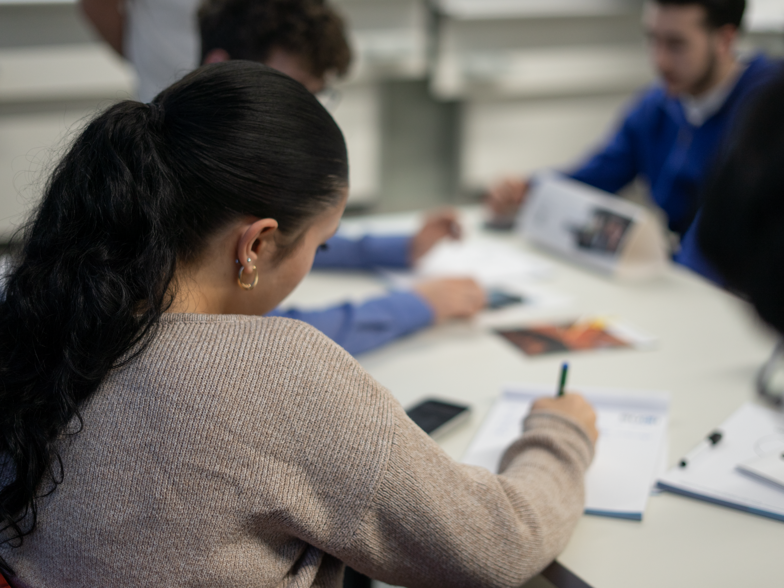 Eine Schülerin sitzt konzentriert im Unterricht und beschäftigt sich aufmerksam mit den Lerninhalten.